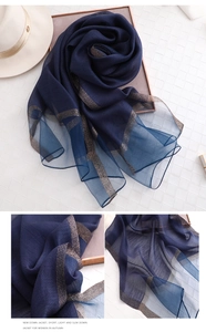 Detail eines marineblauen Chiffonschals mit eleganten Goldpailletten und weichem Stoff