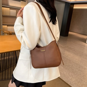 Brown leather tote bag with minimalist fashion design worn by a model on shoulder