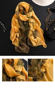Détail de l'écharpe en soie jaune et verte avec broderie florale et finitions à franges