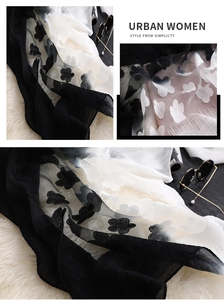 Détail de broderie florale noire et blanche élégante sur une écharpe en soie dégradée