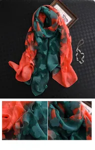 Détail d'une écharpe en soie élégante avec jacquard floral 3D en tons rouge corail et vert