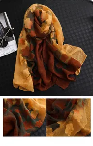 Détail d'une écharpe en soie avec broderies florales orange et texture légère translucide