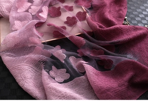 Gros plan d'une écharpe en dégradé rose avec broderie florale 3D et bords à franges