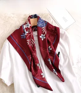 Close-up of red silk square scarf with floral patterns on a white t-shirt