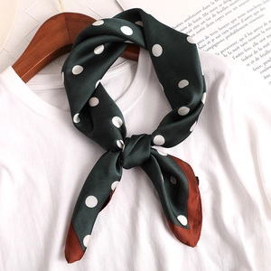 Élégant foulard en soie vert foncé à pois blancs noué sur un t-shirt blanc