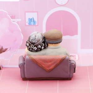 Rear view of elderly couple figurines on purple sofa for cake decoration gift
