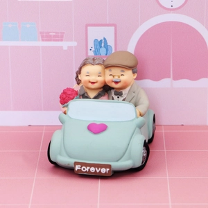 Smiling elderly couple in a blue classic car figurine with Forever license plate decor
