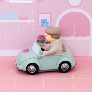Detail of elderly couple in a blue toy car resin figurine with heart and flowers