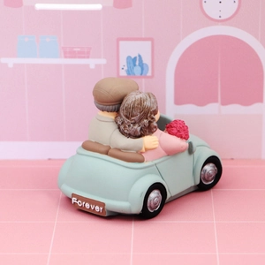 Detail of elderly couple figurine in a light blue vintage car with Forever text on back