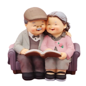 Elderly couple figurines sitting on a sofa for cake decoration and anniversary gifts