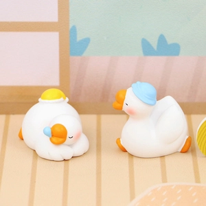 Detail of two mini white goose figurines with cute hats on a pastel pink background