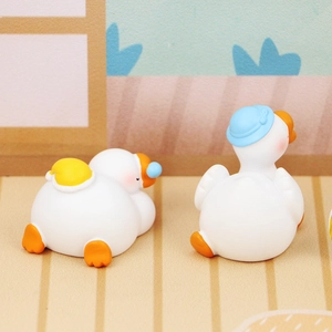 Close-up of cute resin goose figurines with blue hat and shell detail for car decor