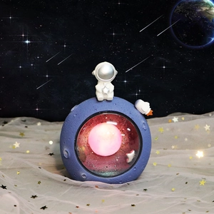 Astronaut night light with glowing pink sphere on blue lunar base and rocket decor