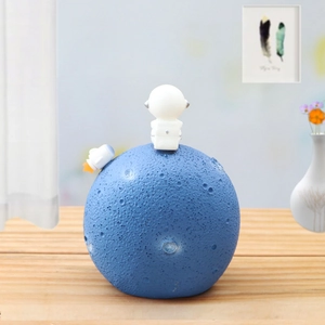 Detailed astronaut ornament featuring deep blue moon crater texture on a wooden desk