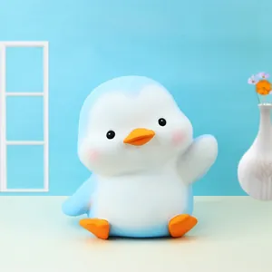 Detail of cute blue penguin money bank for kids on a minimalist desktop with decor