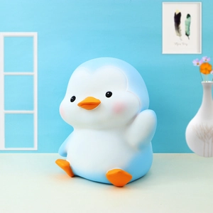 Detail of penguin piggy bank showing matte texture and cute waving pose for kids