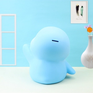 Detail of light blue penguin piggy bank with top coin slot and smooth matte finish