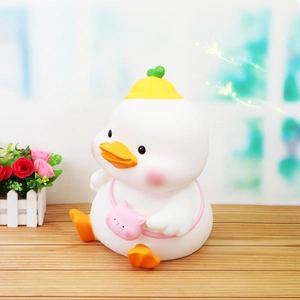 Close-up of cute MOMO duck piggy bank with yellow hat and pink bear bag on wooden table