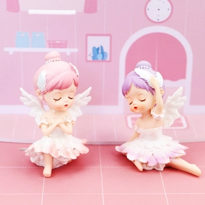 Macro detail of two miniature resin ballet angels with feather wings in pink and purple