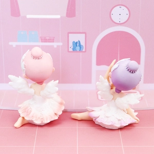 Macro detail of two ballet girl ornaments with feather skirts and wings on a pink background