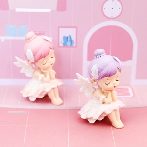 Close-up of ballet angel figurines with wings sitting on pink dreamy background