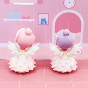 Detailed back view of pink and purple ballerina figurines with delicate white feather wings