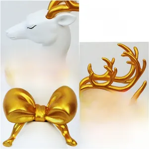 Detailed macro view of white ceramic elk sculpture with matte gold antlers and bow decoration