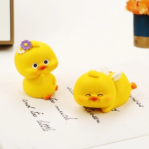 Close-up of two cute yellow resin ducks with flower and wings for car dashboard decor