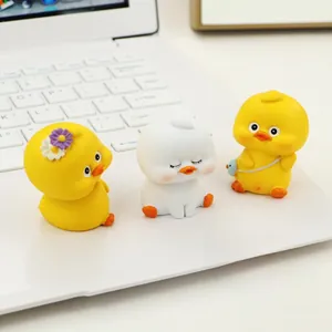 Close-up of three cute resin duck figurines with accessories on a white laptop