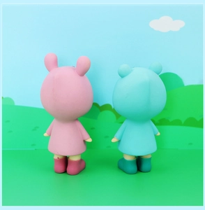 Detail view of pink and blue cartoon figurines in raincoats with artistic hill background