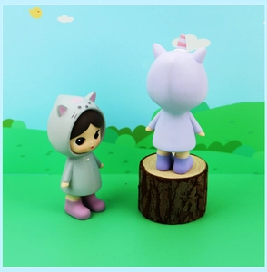 Detail of cute doll in cat hoodie and unicorn companion on wooden stump stand