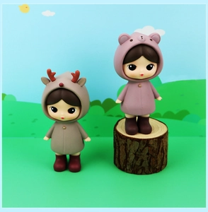Detail of two cute collectible dolls wearing deer and bear hoodies on scenic background