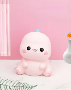 Détail d'une adorable tirelire dinosaure rose sur une table en marbre élégante