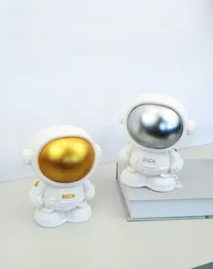 Detail of gold and silver astronaut piggy banks with 'RICH' engraving on modern display