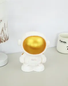 Detail of white astronaut money box with gold face mask and Rich logo on chest