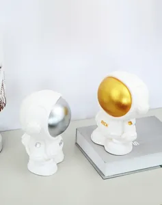 Close-up of astronaut piggy bank ornaments with high-gloss gold and silver face masks