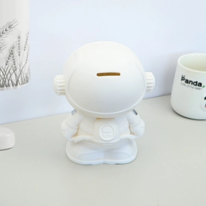 Rear view of white astronaut money box showing coin slot and smooth matte finish