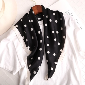 Gros plan sur un foulard en soie à pois noirs et blancs avec une texture lisse et bordure