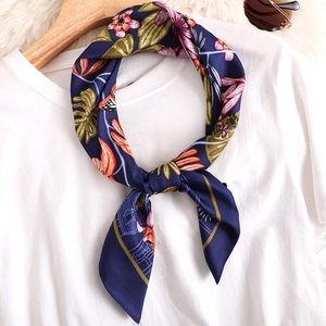 Elegant navy blue floral silk square scarf tied on a white t-shirt and wooden hanger