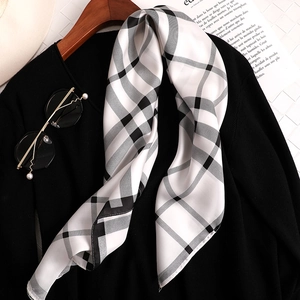 Gros plan d'un foulard en soie à damier noir et blanc sur un cintre de mode