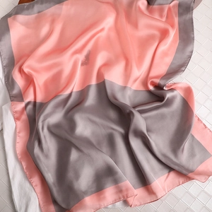 Détail d'une écharpe en soie bicolore rose et gris avec une texture satinée lisse