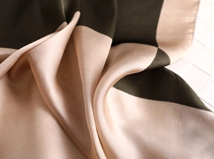 Détail d'un foulard en soie avec blocs de couleur vert foncé et champagne et éclat satiné