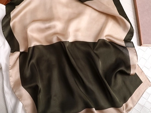 Détail d'une écharpe en satin élégante montrant une texture patchwork vert et doré