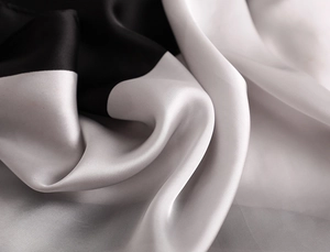 Détail de foulard en satin de soie noir et gris élégant montrant une texture lisse et brillante
