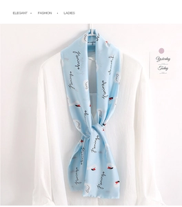 Detail of light blue silk scarf featuring pink flamingo prints and fringed edges