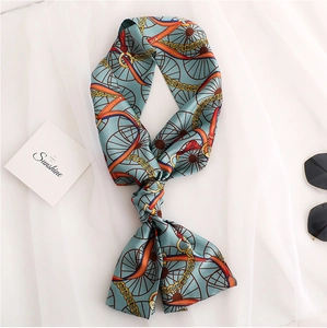 Detail of blue twilly scarf with retro chain print and tassel on white silk background