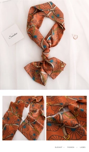 Detail of vintage orange silk scarf with gold chain and wheel print on white fabric