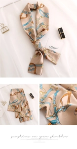 Detail of silk twilly scarf with blue chain pattern on beige fabric with soft lighting