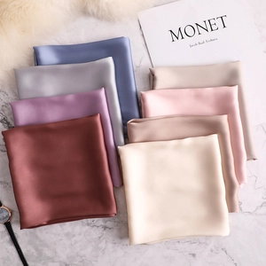 Elegant satin silk square scarves in assorted Morandi colors on white marble surface