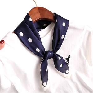 Élégant foulard en soie bleu marine à pois noué sur un t-shirt blanc en coton classique
